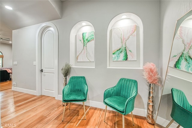 living area with baseboards, wood finished floors, and a ceiling fan