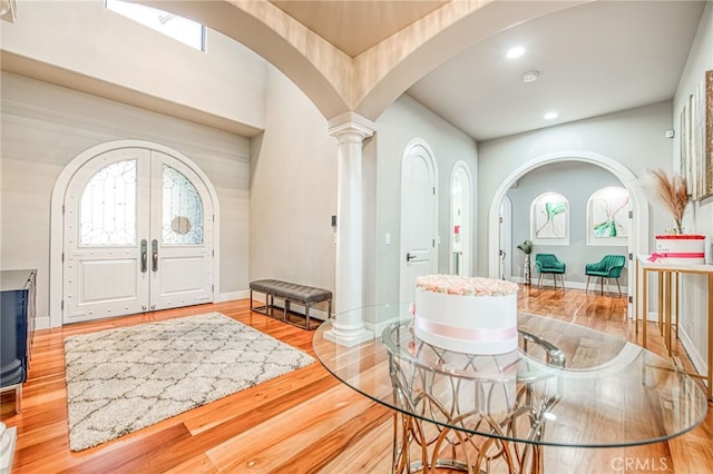 foyer entrance with baseboards, arched walkways, wood finished floors, and ornate columns