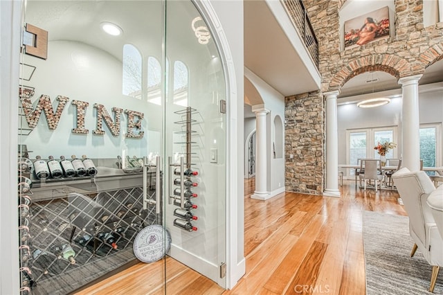 wine area with wood-type flooring and decorative columns