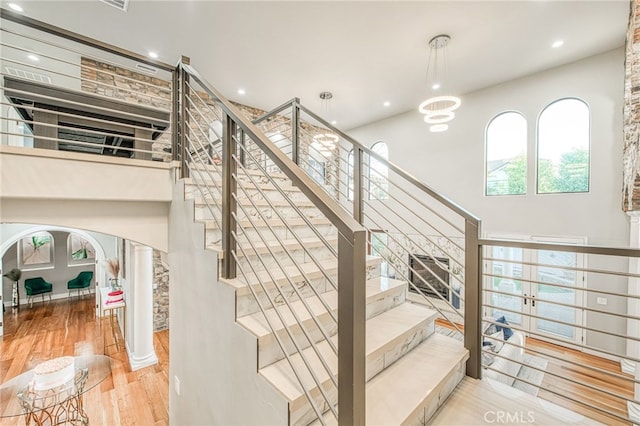 staircase featuring recessed lighting, wood finished floors, and ornate columns