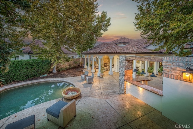 pool at dusk featuring a patio and a fenced in pool