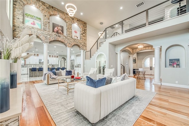 living room featuring arched walkways, visible vents, wood finished floors, and decorative columns