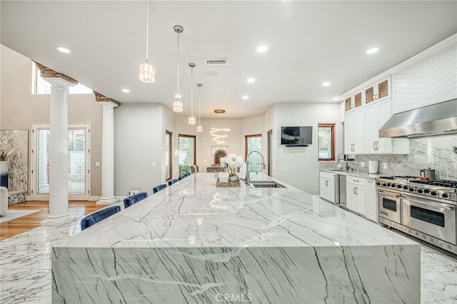 kitchen with light stone countertops, stainless steel appliances, and decorative columns