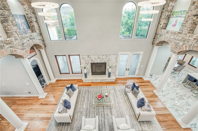 living room with visible vents, a fireplace, ornate columns, and wood finished floors