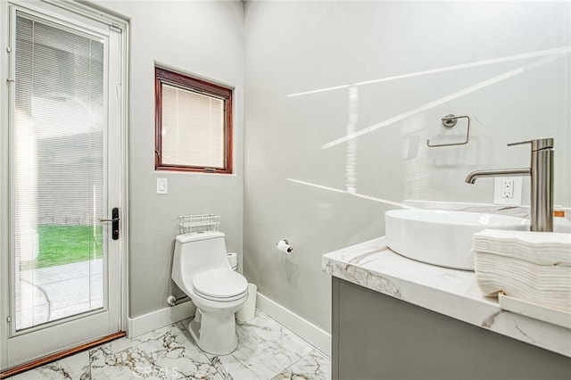 bathroom with marble finish floor, toilet, vanity, and baseboards