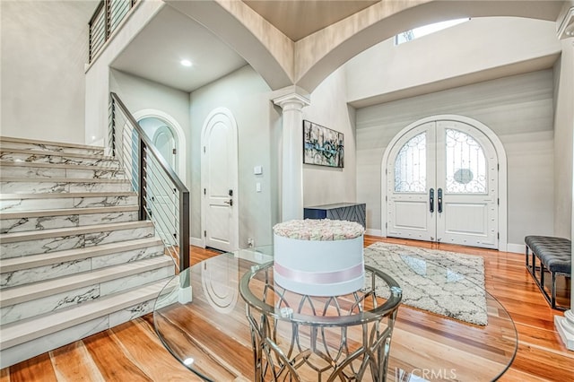 entryway featuring stairs, french doors, wood finished floors, arched walkways, and ornate columns