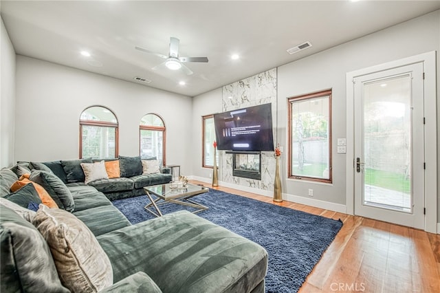 living area with ceiling fan, visible vents, a healthy amount of sunlight, and wood finished floors