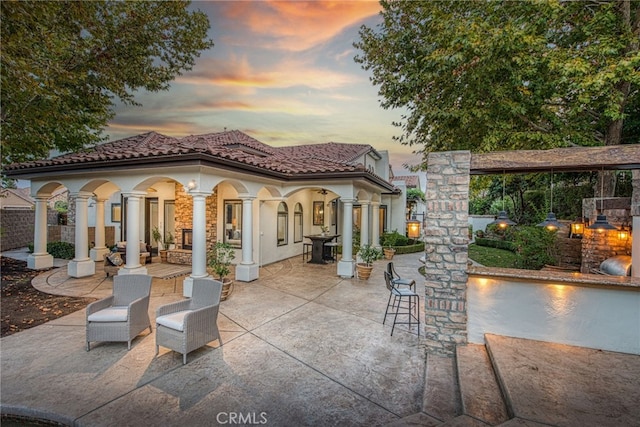 patio terrace at dusk featuring a fireplace