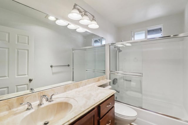 bathroom featuring enclosed tub / shower combo, toilet, and vanity