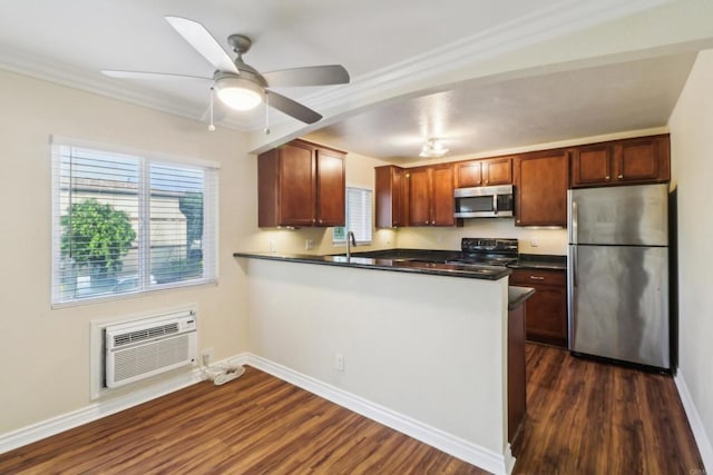 kitchen featuring dark countertops, dark wood-style floors, appliances with stainless steel finishes, and a peninsula