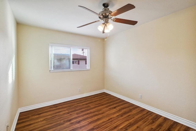 spare room with dark wood finished floors, a ceiling fan, and baseboards