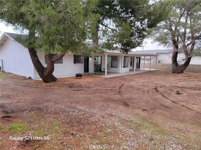 rear view of house with stucco siding and a patio area