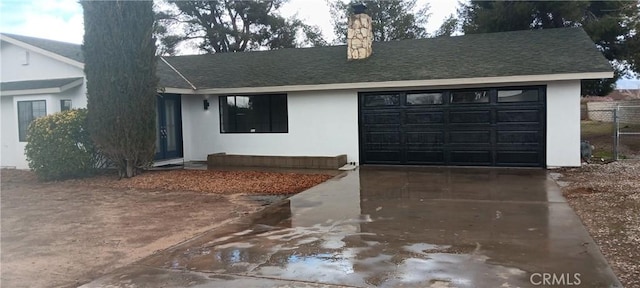 ranch-style house with a shingled roof, driveway, and stucco siding