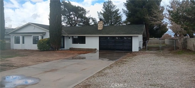 ranch-style home featuring fence, an attached garage, stucco siding, a chimney, and concrete driveway