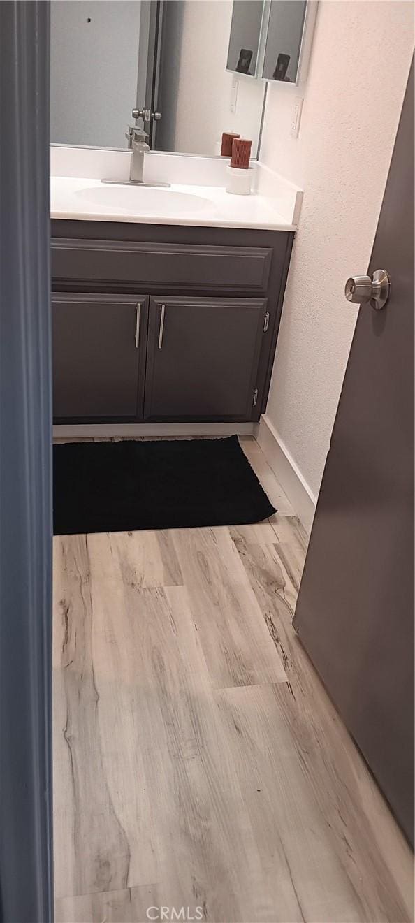 bathroom featuring vanity, baseboards, and wood finished floors