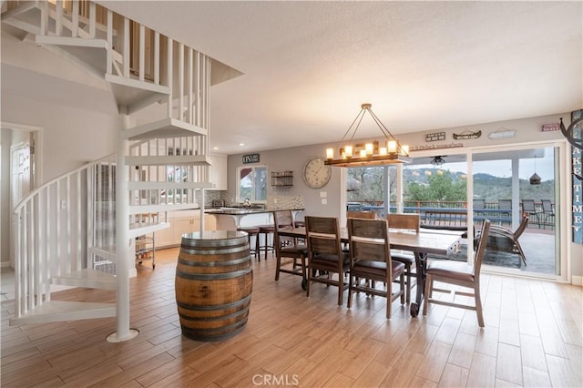 dining area featuring an inviting chandelier, stairway, and light wood-style flooring