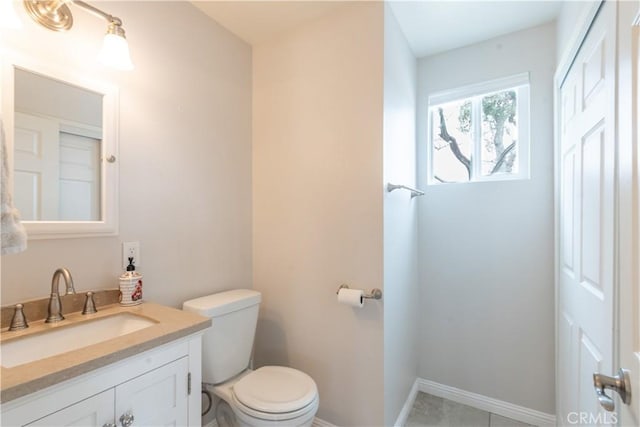 bathroom with toilet, vanity, and baseboards