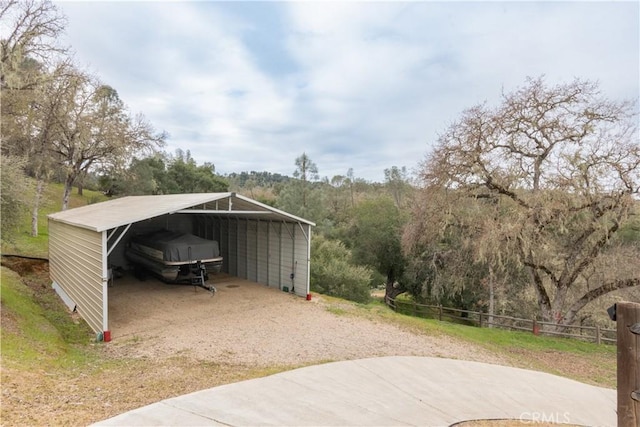 view of outdoor structure featuring a detached carport and fence