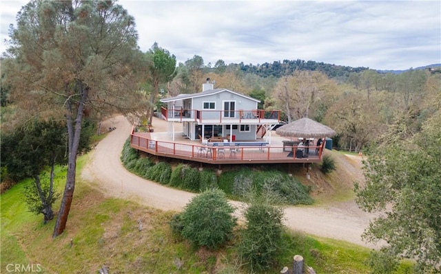 rear view of house with a gazebo, a wooded view, driveway, and a wooden deck