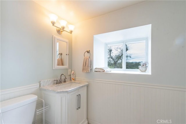 bathroom featuring vanity, toilet, and wainscoting