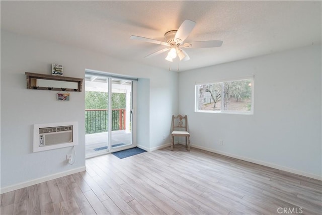 empty room featuring ceiling fan, baseboards, an AC wall unit, and wood finished floors