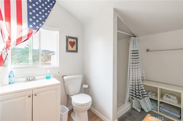 bathroom with toilet, a shower with shower curtain, baseboards, vanity, and vaulted ceiling