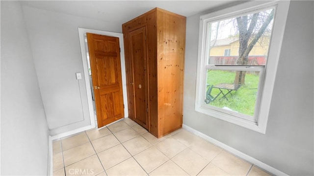 spare room featuring light tile patterned flooring, baseboards, and plenty of natural light