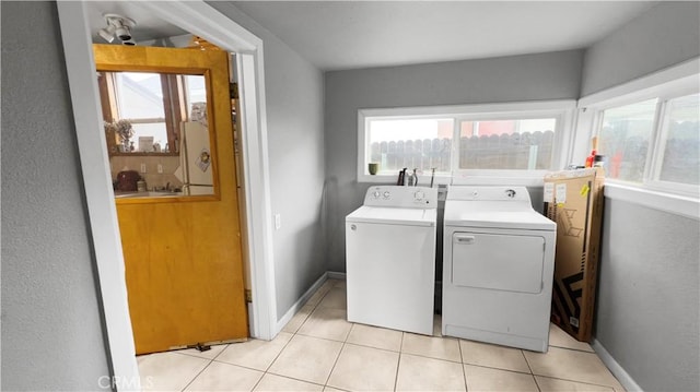 washroom with separate washer and dryer, laundry area, baseboards, and light tile patterned flooring