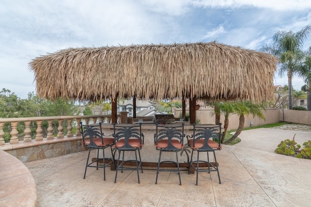 view of patio with outdoor dry bar and fence