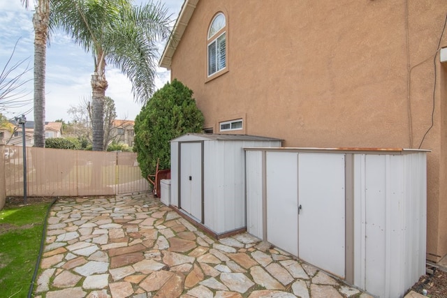 view of patio / terrace featuring a storage shed, an outdoor structure, and fence