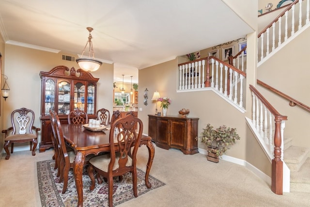 carpeted dining space featuring stairs, crown molding, baseboards, and visible vents