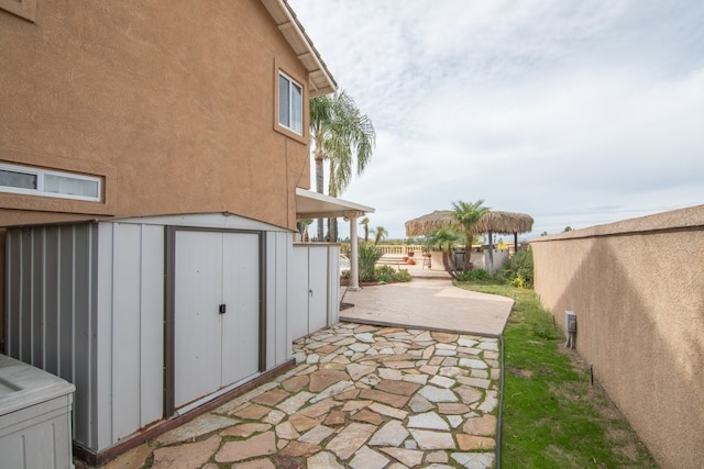 view of yard with a patio, a storage shed, an outbuilding, and fence