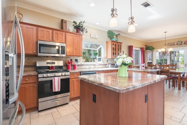 kitchen with a healthy amount of sunlight, visible vents, decorative backsplash, appliances with stainless steel finishes, and brown cabinets