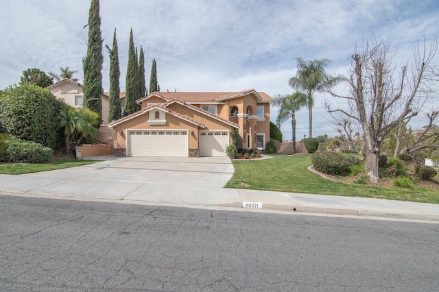 mediterranean / spanish-style home featuring a front lawn, concrete driveway, a garage, and stucco siding