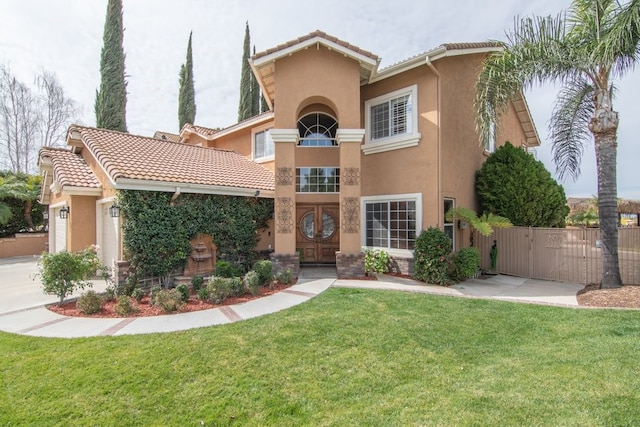 mediterranean / spanish home with a gate, stucco siding, a front lawn, a garage, and a tiled roof