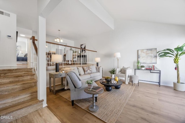 living area featuring stairs, an inviting chandelier, wood finished floors, and visible vents