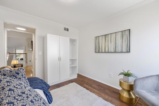 bedroom with baseboards, wood finished floors, visible vents, and ornamental molding