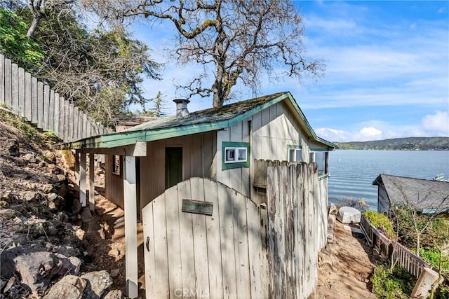 view of outdoor structure featuring a water view and fence