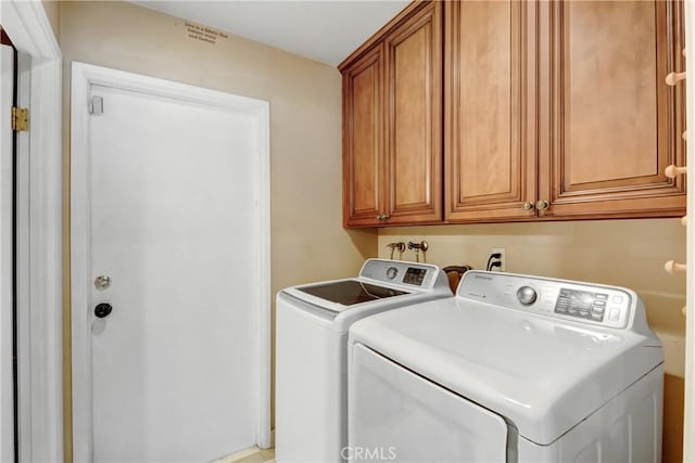 clothes washing area with washer and dryer and cabinet space