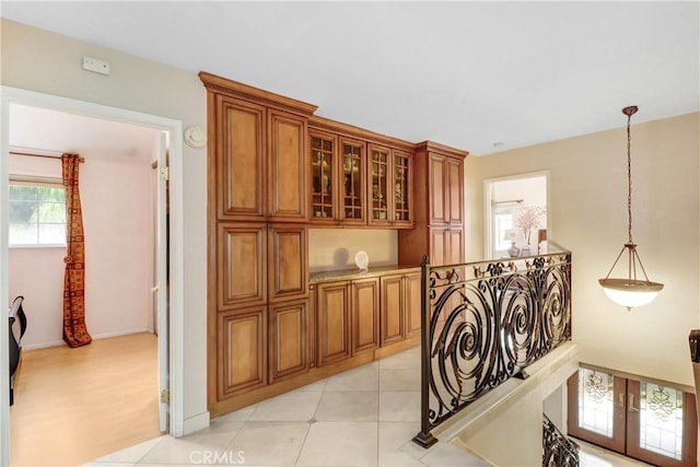 corridor featuring light tile patterned floors and an upstairs landing