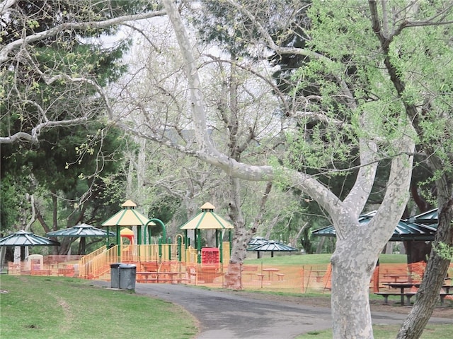 view of property's community with playground community, a yard, and fence