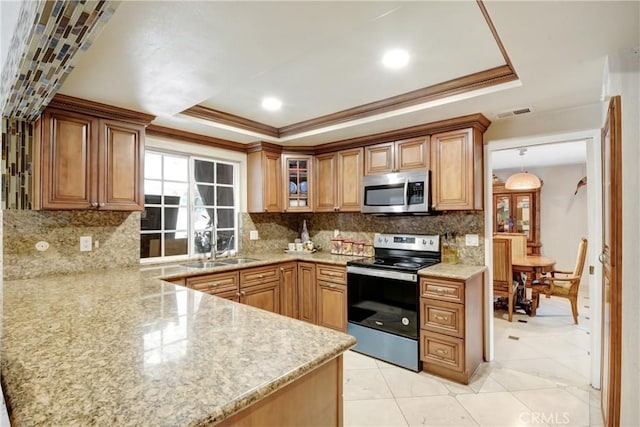 kitchen featuring a sink, a tray ceiling, backsplash, stainless steel appliances, and glass insert cabinets