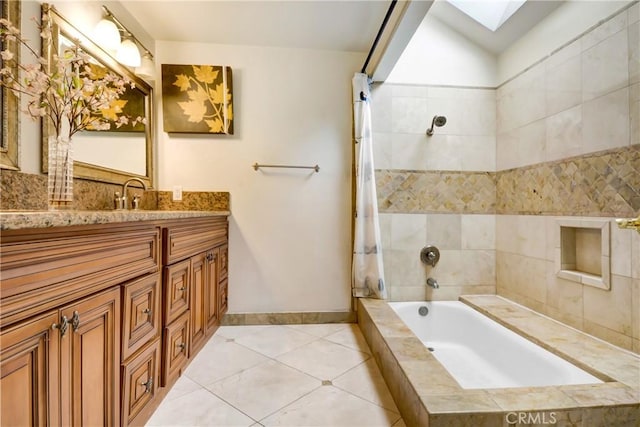 full bathroom with tile patterned flooring, baseboards, a skylight, tiled shower / bath combo, and vanity