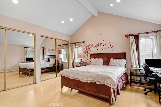 bedroom with vaulted ceiling with beams, multiple windows, two closets, and light wood-style floors