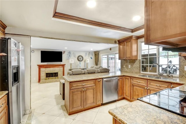 kitchen with a peninsula, a sink, crown molding, appliances with stainless steel finishes, and a raised ceiling