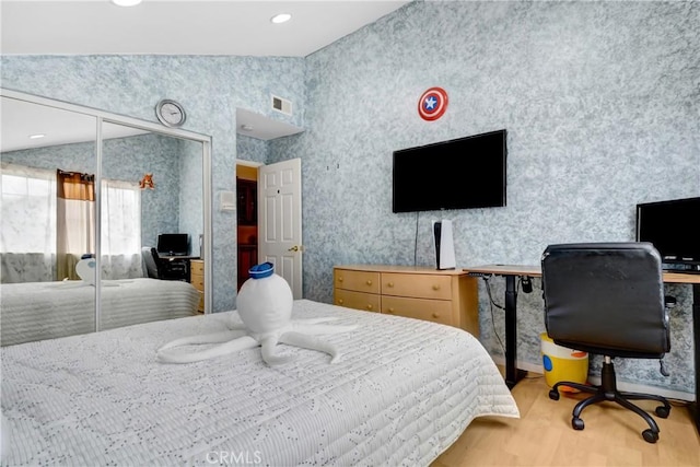 bedroom with wallpapered walls, lofted ceiling, wood finished floors, and visible vents