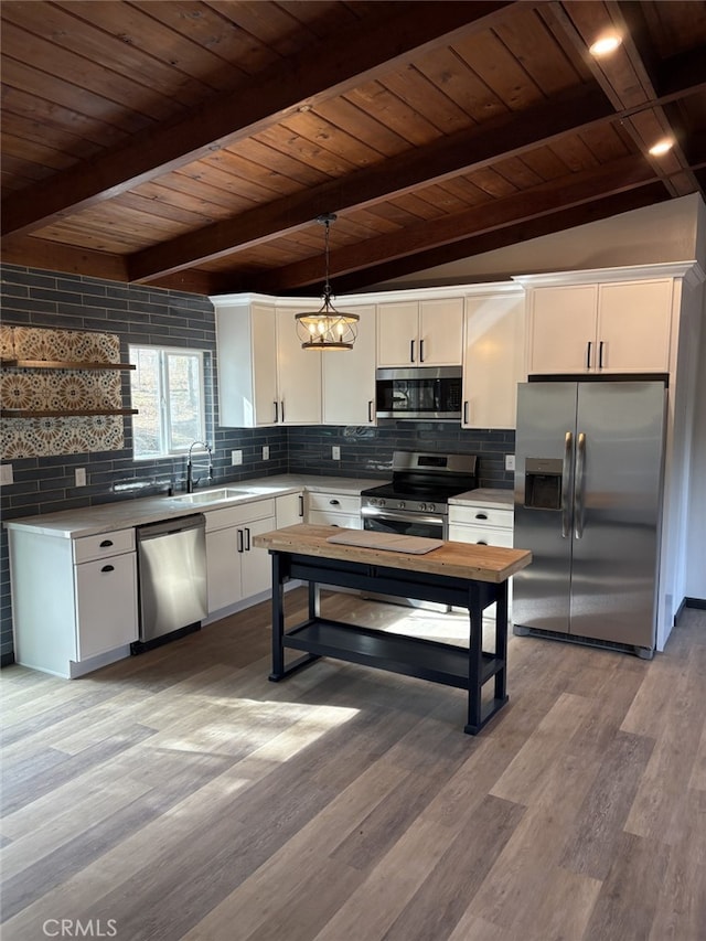 kitchen with backsplash, decorative light fixtures, stainless steel appliances, white cabinetry, and a sink