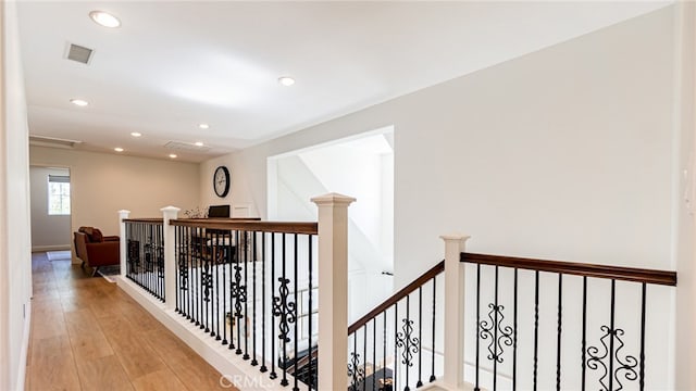 hall with recessed lighting, visible vents, an upstairs landing, and light wood-style floors