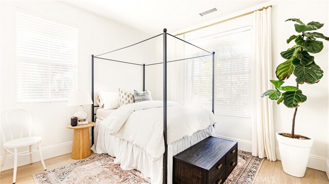 bedroom featuring wood finished floors, visible vents, and baseboards