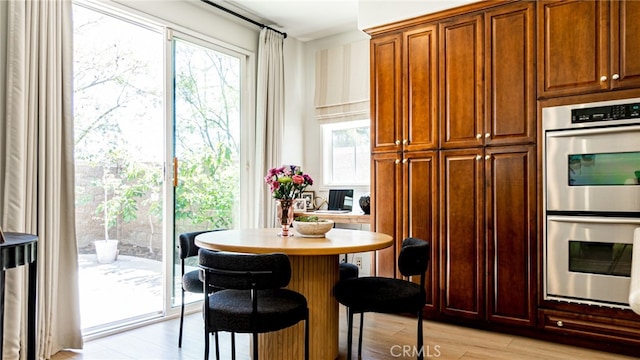 kitchen with a breakfast bar area, double oven, light wood-style flooring, and light countertops